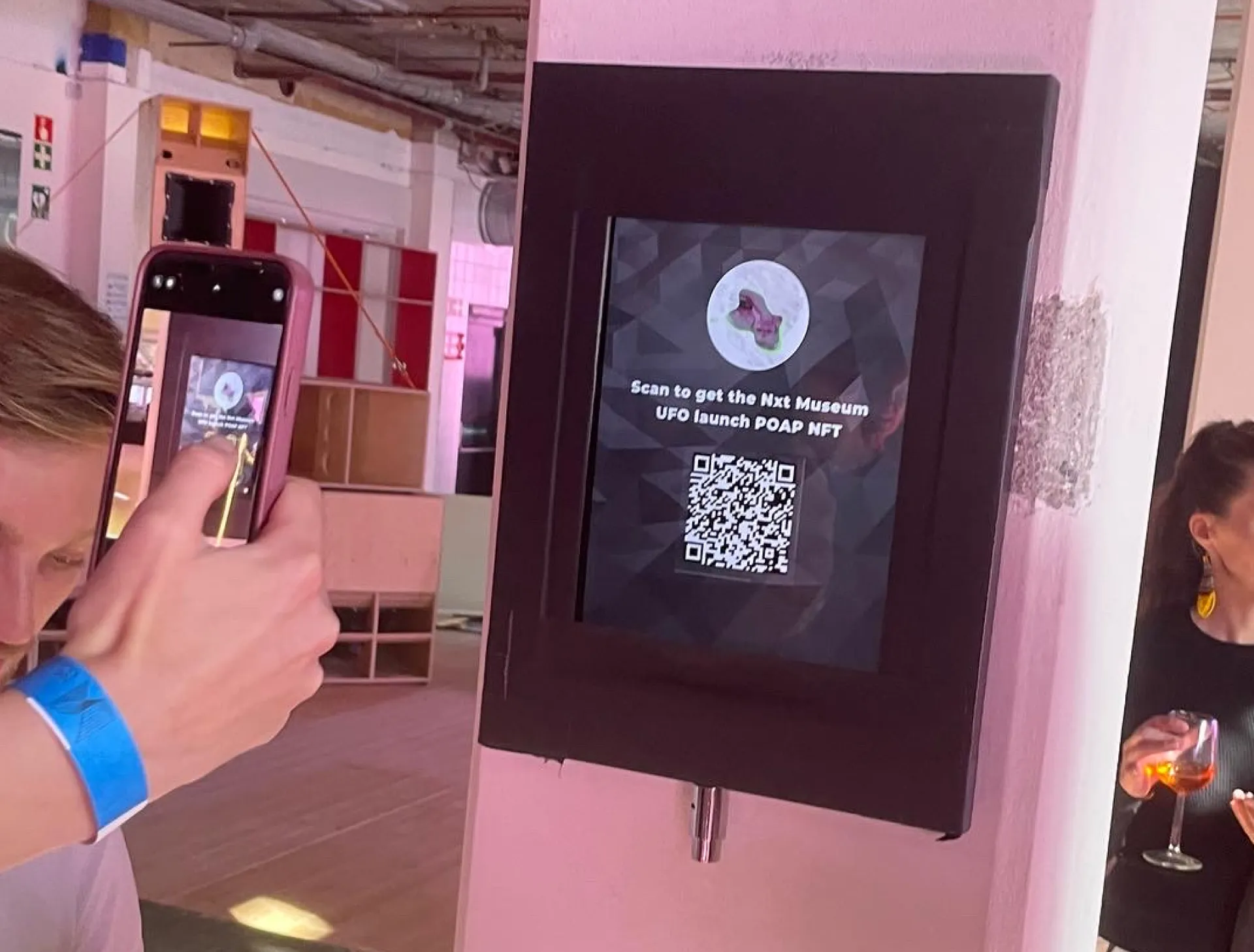 Visitor scanning a dynamic QR code on an in-gallery screen to claim the Nxt Museum UFO POAP